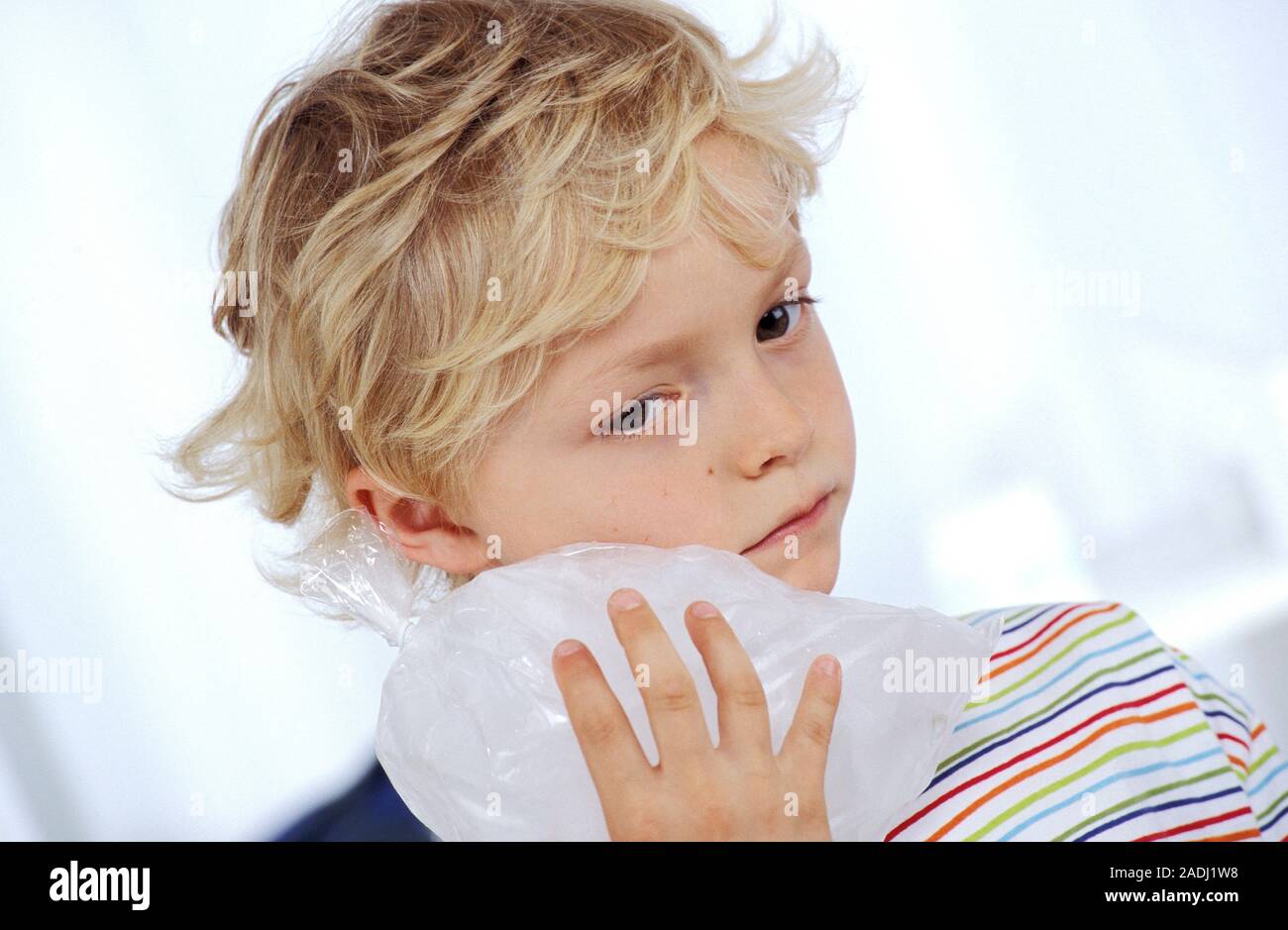 MODEL RELEASED. Toothache. Sixyearold boy holding an ice pack against