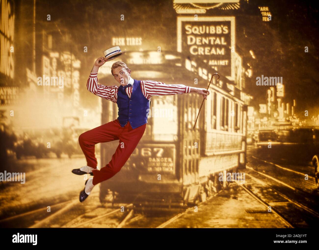 1970s VAUDEVILLE ERA TAP DANCING MAN JUMPING UP AND CLICKING HIS HEELS TOGETHER WITH SEPIA TONED 1920s SCENE OF TIMES SQUARE NYC - kd2845 PHT001 HARS YOUNG ADULT LEAPING MANHATTAN JOY LIFESTYLE SATISFACTION ACTOR CELEBRATION STUDIO SHOT CANE UNITED STATES COPY SPACE FULL-LENGTH PERSONS INSPIRATION UNITED STATES OF AMERICA MALES ENTERTAINMENT CONFIDENCE VEST TAP EYE CONTACT PERFORMING ARTS ACT DREAMS MIDTOWN HAPPINESS HIS LEAP PERFORMER AND EXCITEMENT GOTHAM PRIDE UP VAUDEVILLE ENTERTAINER NYC OCCUPATIONS TROLLEY CONCEPTUAL NEW YORK STRAW HAT ACTORS CITIES SEPIA STYLISH NEW YORK CITY Stock Photo