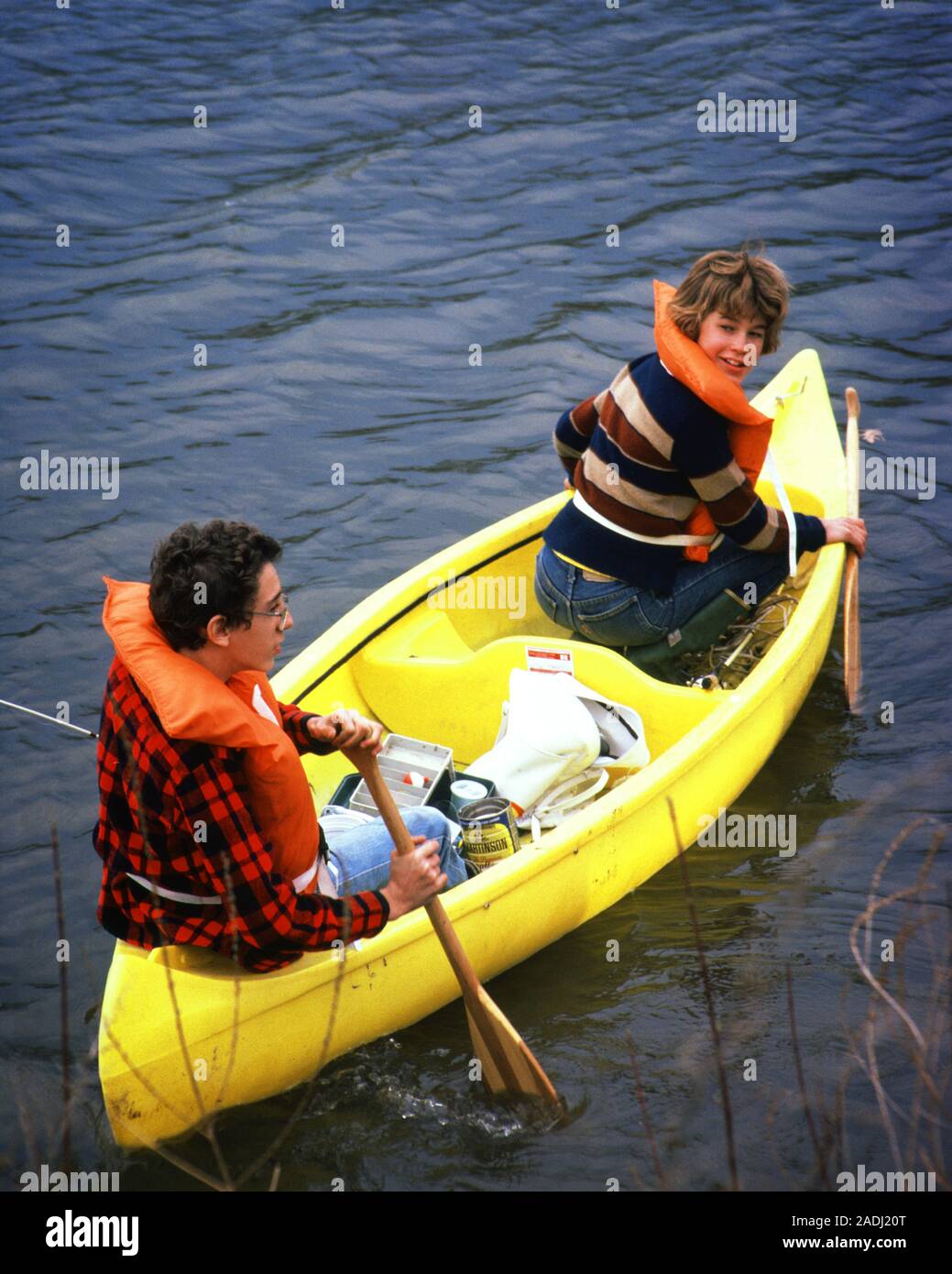 1980s PRETEEN BOY AND GIRL WEARING SAFETY ORANGE LIFE JACKETS HE PADDLING YELLOW PLASTIC CANOE IN WATER SHE LOOKING AT CAMERA - kc9237 PHT001 HARS RIVER NOSTALGIA BROTHER OLD FASHION SISTER 1 JUVENILE VEHICLE BALANCE SAFETY TEAMWORK VACATION CANOE ATHLETE PLEASED JOY LIFESTYLE FEMALES BROTHERS RURAL HOME LIFE TRANSPORT COPY SPACE FRIENDSHIP HALF-LENGTH PERSONS STREAM MALES RISK ATHLETIC SIBLINGS CONFIDENCE ORANGE SISTERS TRANSPORTATION EYE CONTACT DATING TIME OFF CANOEING HAPPINESS CHEERFUL HIGH ANGLE ADVENTURE PROTECTION AND GETAWAY EXCITEMENT RECREATION SHE IN HOLIDAYS OARS PRETEEN SIBLING Stock Photo