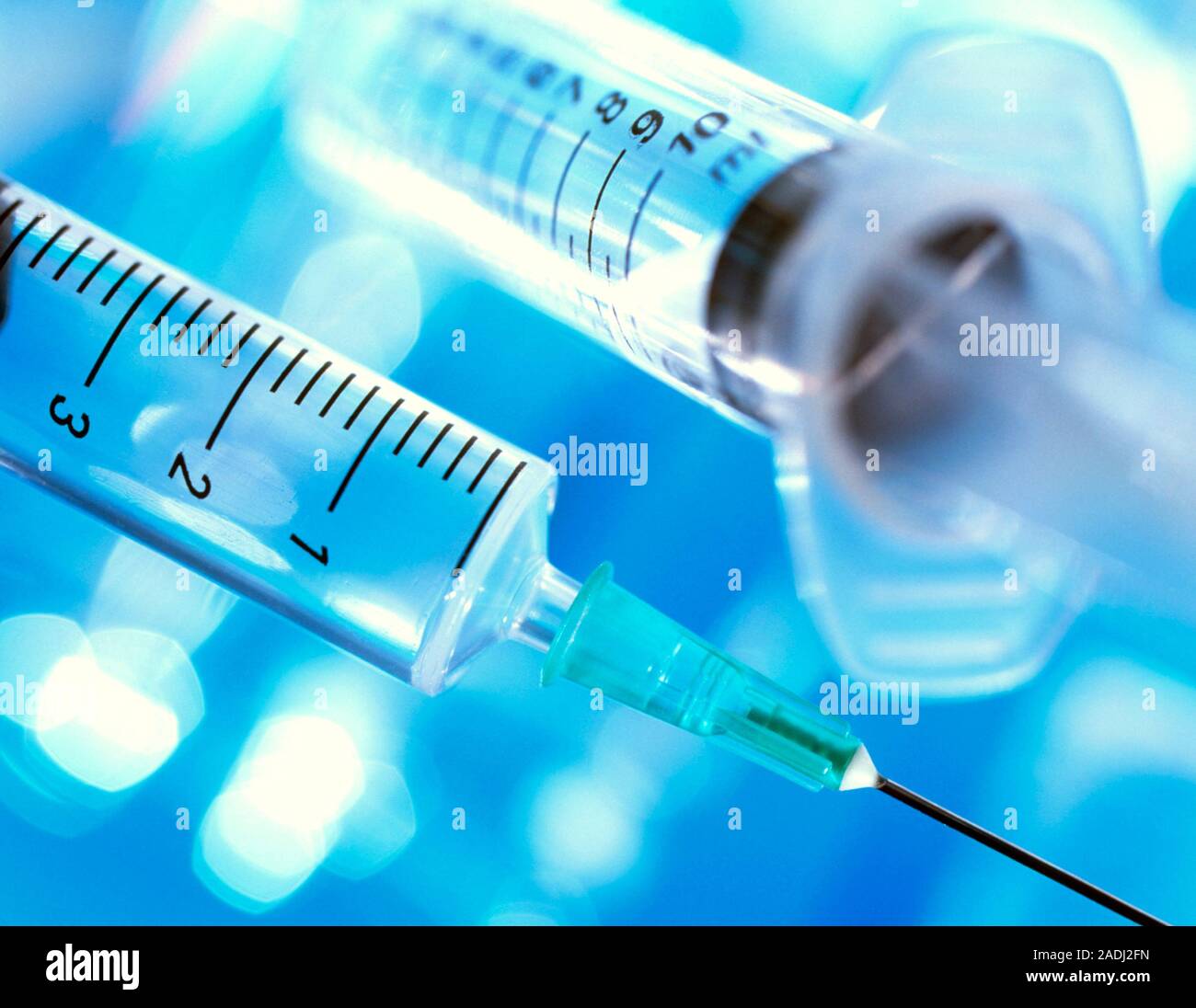 Syringes. Two hypodermic syringes. The lower one has a needle attached