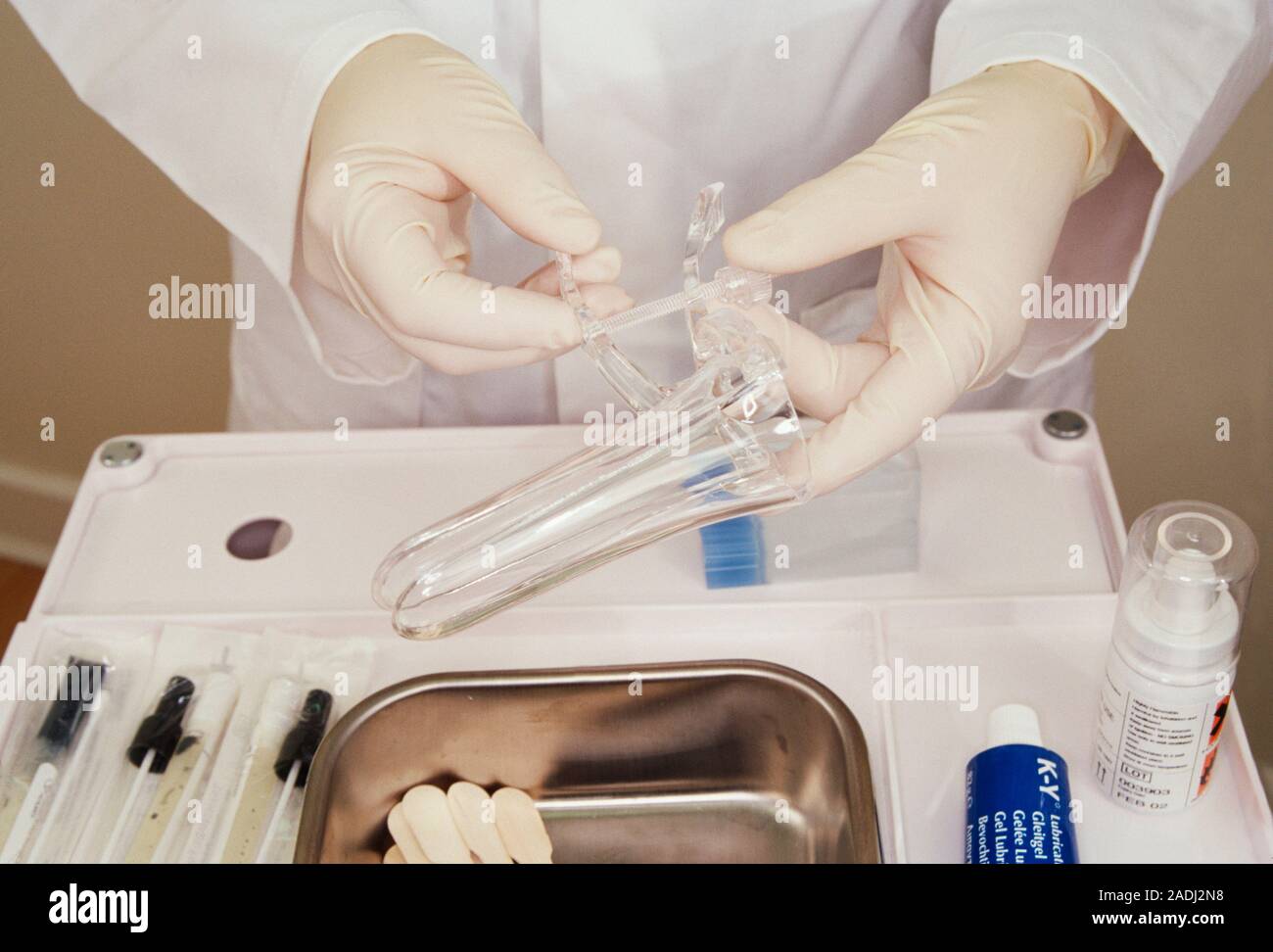 Gynaecological equipment. Gloved hand holding a vaginal Cusco speculum over a metal tray with