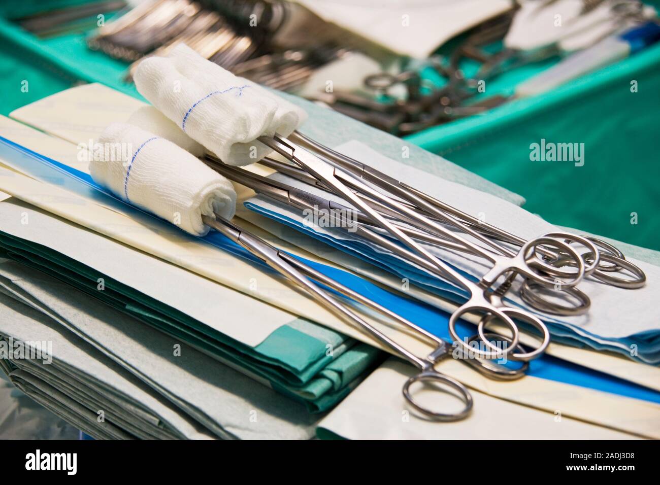Surgical swabs held by forceps, resting on folded surgical drapes and towels. These absorbent