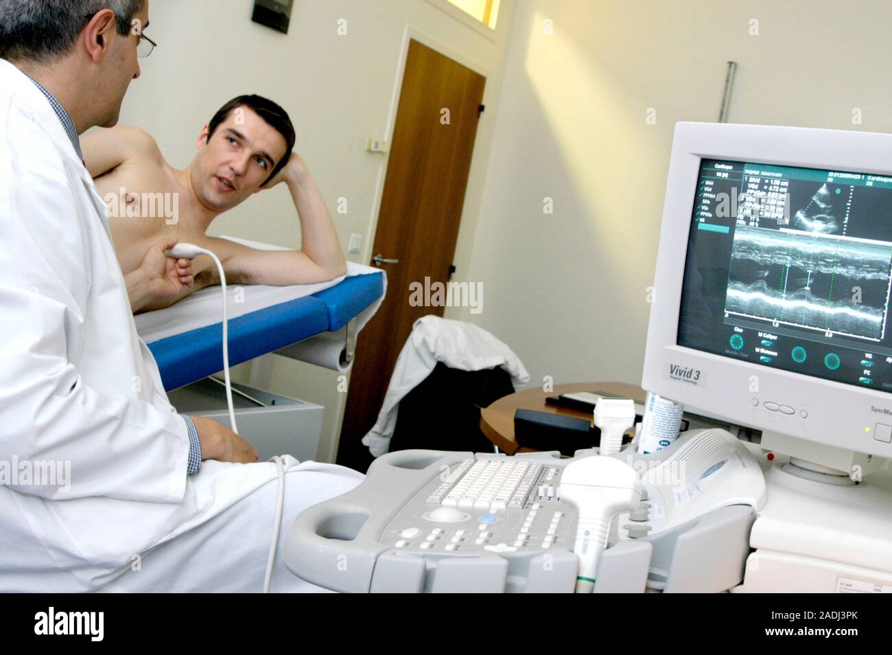 MODEL RELEASED. Echocardiography. 30-year-old patient undergoing a heart ultrasound scan. A transducer, held against his chest, emits ultrasonic waves Stock Photo