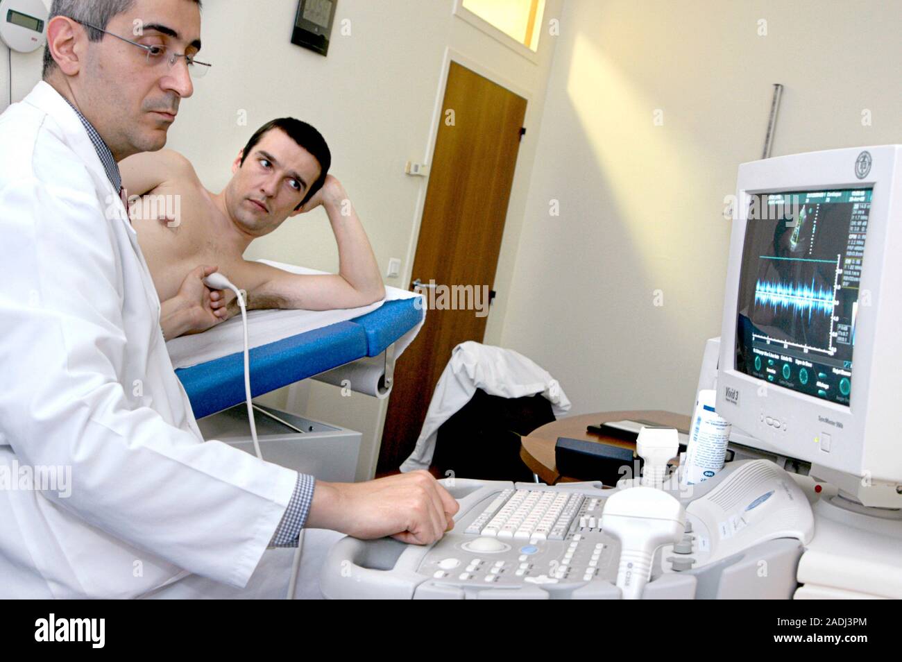 MODEL RELEASED. Echocardiography. 30-year-old patient undergoing a heart ultrasound scan. A transducer, held against his chest, emits ultrasonic waves Stock Photo