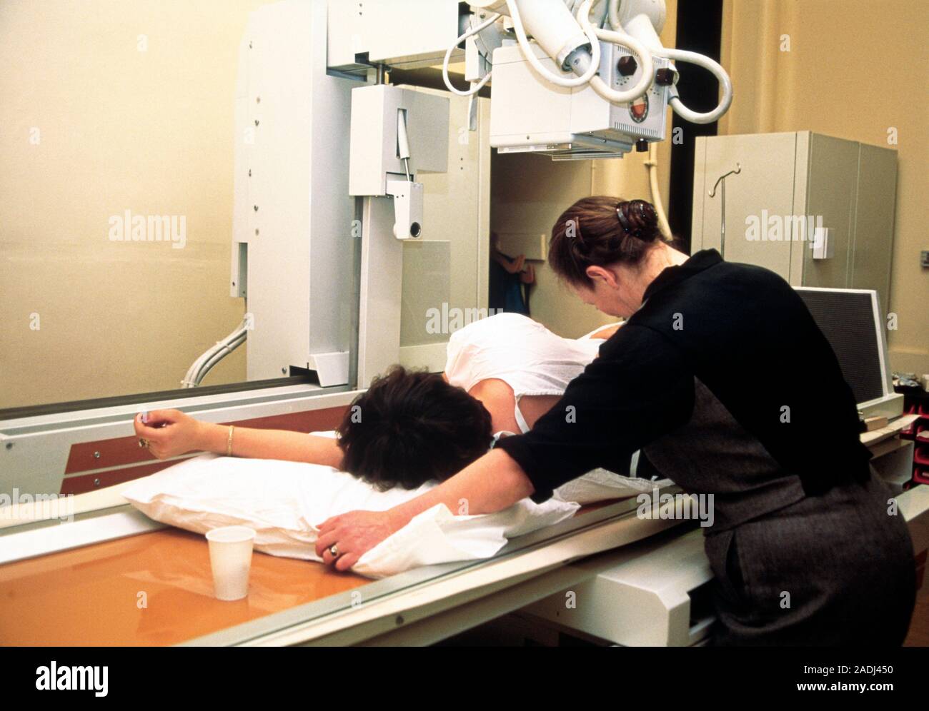 Barium meal X-ray. Radiologist positioning a female patient for an ...