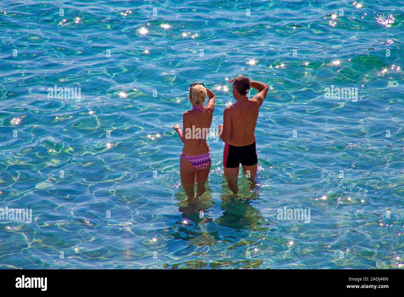 Young couple standing in shallow water at bathing beach of Sant Elm, San Telmo, Mallorca, Balearic islands, Spain Stock Photo