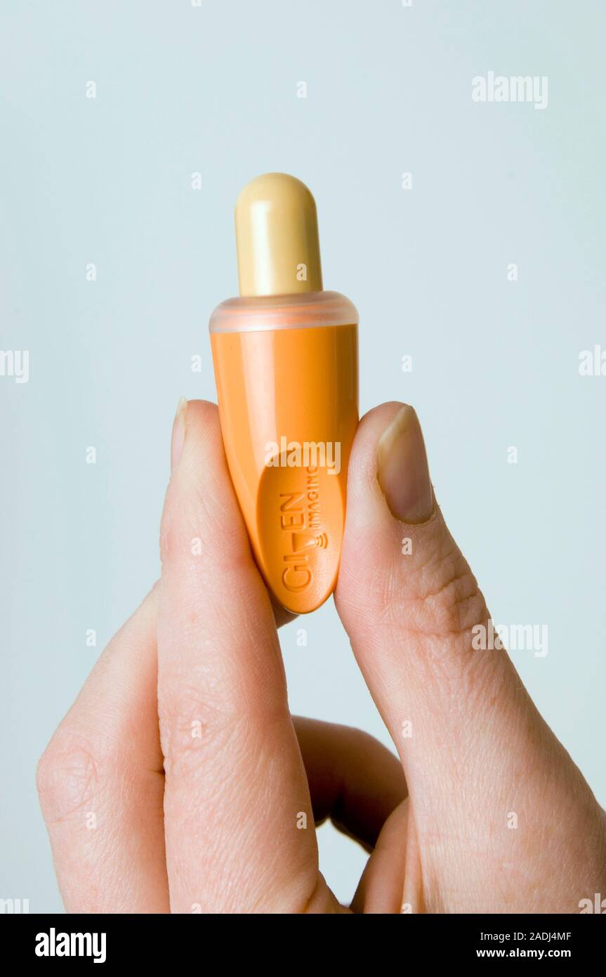 Pill camera. Hand holding a pill camera in a protective dispenser. The