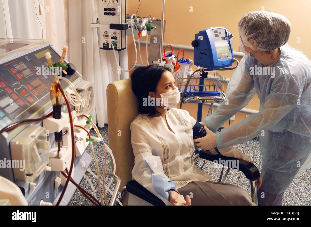 Kidney dialysis. Nurse checking a patient's blood pressure before starting renal dialysis