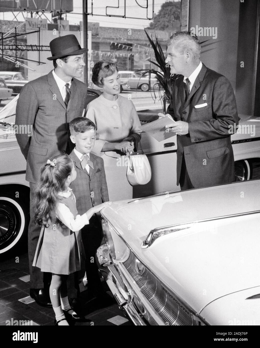 1960s FAMILY DAD MOM BOY GIRL BUYING A NEW CAR WITH
