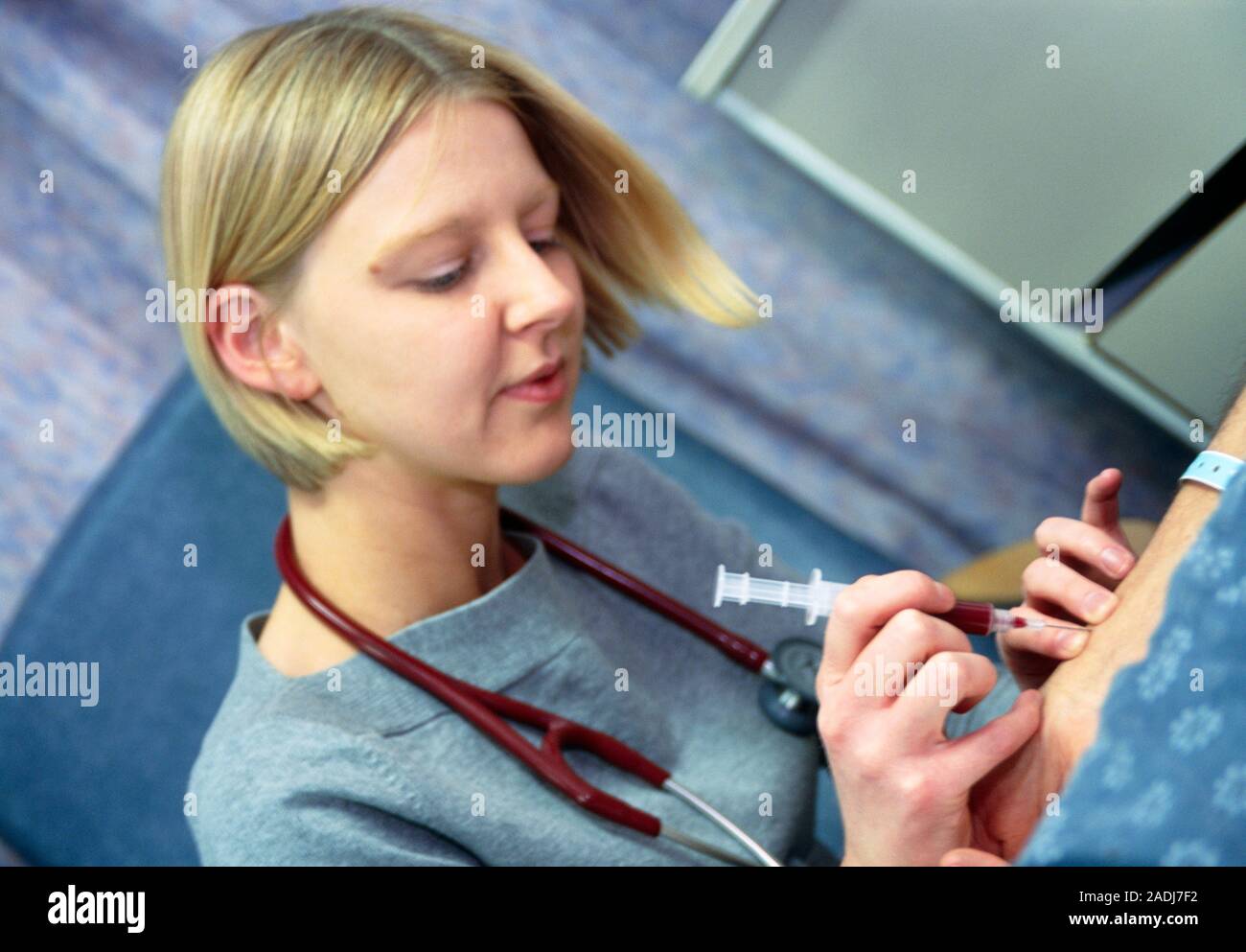 Doctor Sampling Blood sampling. Doctor using a syringe to take a blood sample from the ...