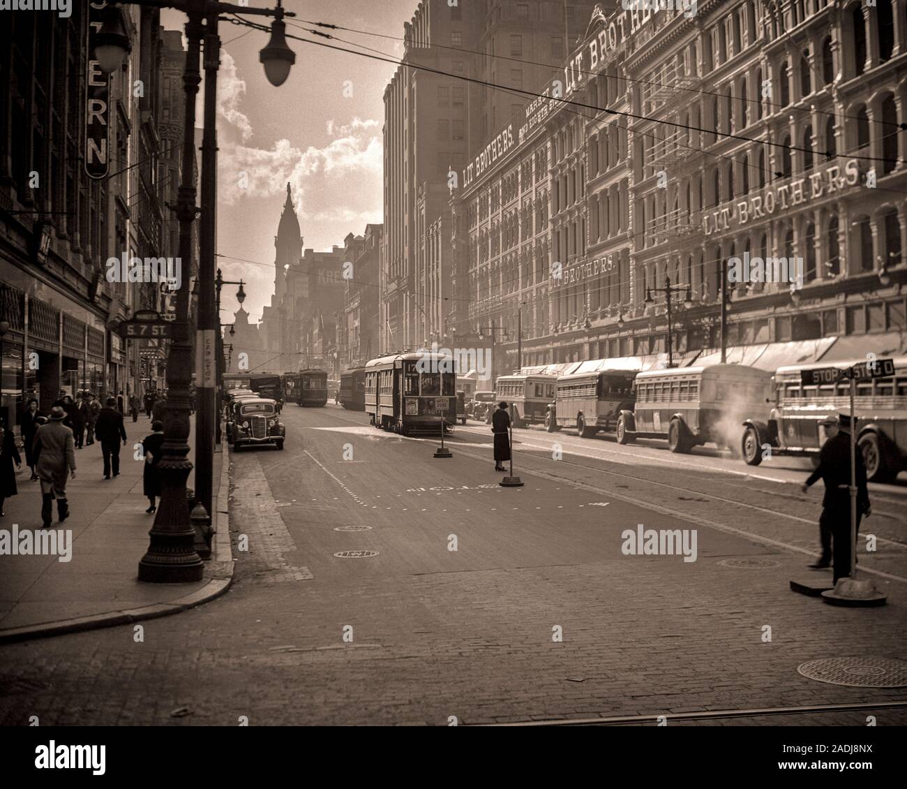 1930s LOOKING WEST MARKET STREET TO CITY HALL TROLLEY CARS TRAFFIC DEPARTMENT STORES  LIT BROTHERS BUILDINGS PHILADELPHIA PA USA - q41888 CPC001 HARS STORES TROLLEY REAL ESTATE STRUCTURES STYLISH EDIFICE BUSES LIT BROTHERS BLACK AND WHITE OLD FASHIONED Stock Photo