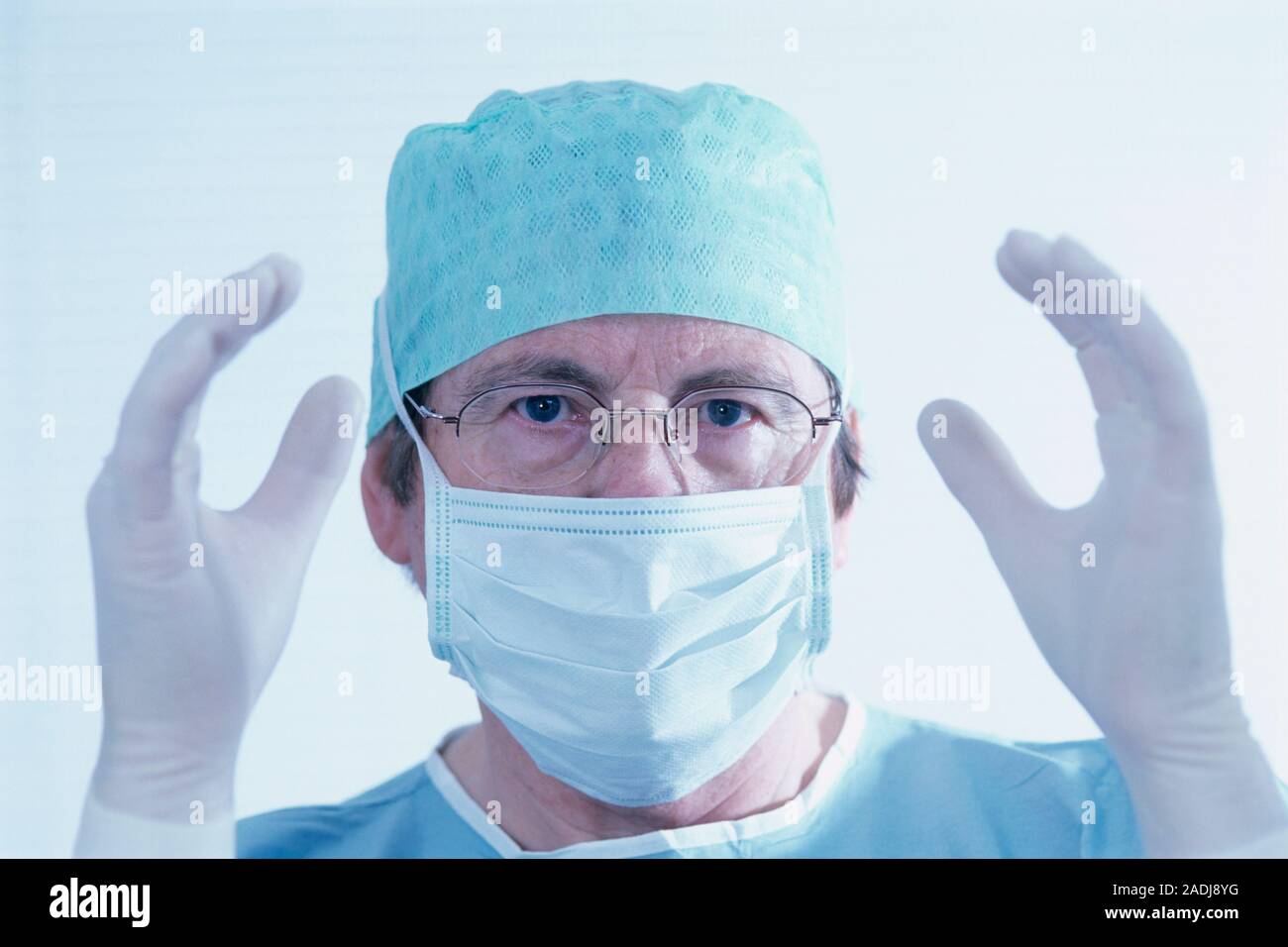 MODEL RELEASED. Surgeon wearing a surgical mask, cap and disposable ...