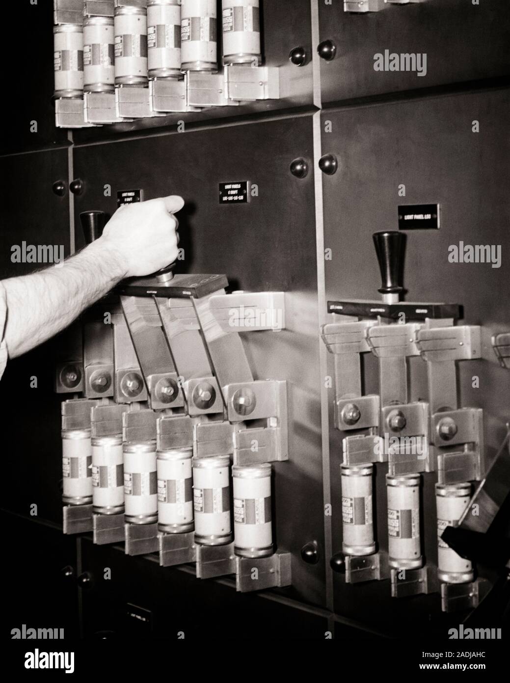1940s 1950s INDUSTRIAL ELECTRIC CURRENT CONTROL PANEL WITH CARTRIDGE FUSES MALE HAND PULLING DOWN SWITCH ON MASTER CONTROL - s15640 HAR001 HARS PANEL SKILL OCCUPATION SKILLS POWERFUL ON MASTER OCCUPATIONS HIGH TECH CONCEPT CONNECTION CONCEPTUAL CURRENT SYMBOLIC CONCEPTS MID-ADULT MID-ADULT MAN BLACK AND WHITE CAUCASIAN ETHNICITY GRID HANDS ONLY HAR001 OLD FASHIONED REPRESENTATION Stock Photo