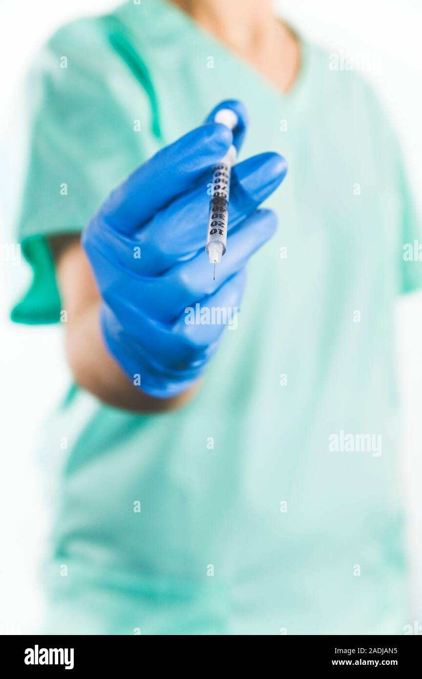 Anaesthetic. Anaesthetist holding a hypodermic syringe. The blue gloves