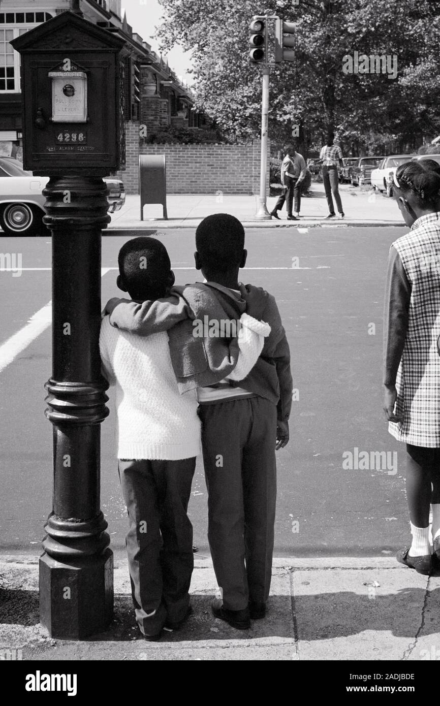 1960s BACK VIEW TWO YOUNG ANONYMOUS SILHOUETTED AFRICAN AMERICAN BOYS ARM IN ARM WAITING TO CROSS STREET AT THE TRAFFIC LIGHT - s17241 HAR001 HARS CARING DANGER MALES RISK SIBLINGS CONFIDENCE B&W ADVENTURE PROTECTION STRATEGY SILHOUETTED AFRICAN-AMERICANS AFRICAN-AMERICAN ARM IN ARM BLACK ETHNICITY AT THE TO SIBLING CONNECTION CONCEPTUAL SUPPORT TRAFFIC LIGHT ANONYMOUS SUPPORTING ASSISTING BACK VIEW GROWTH JUVENILES TOGETHERNESS BLACK AND WHITE HAR001 OLD FASHIONED AFRICAN AMERICANS Stock Photo