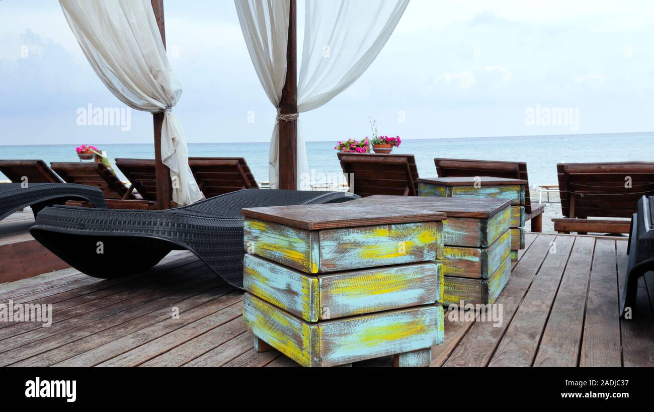 Beach loungers, rustic wooden boxes in a local bar with the sea view Stock Photo