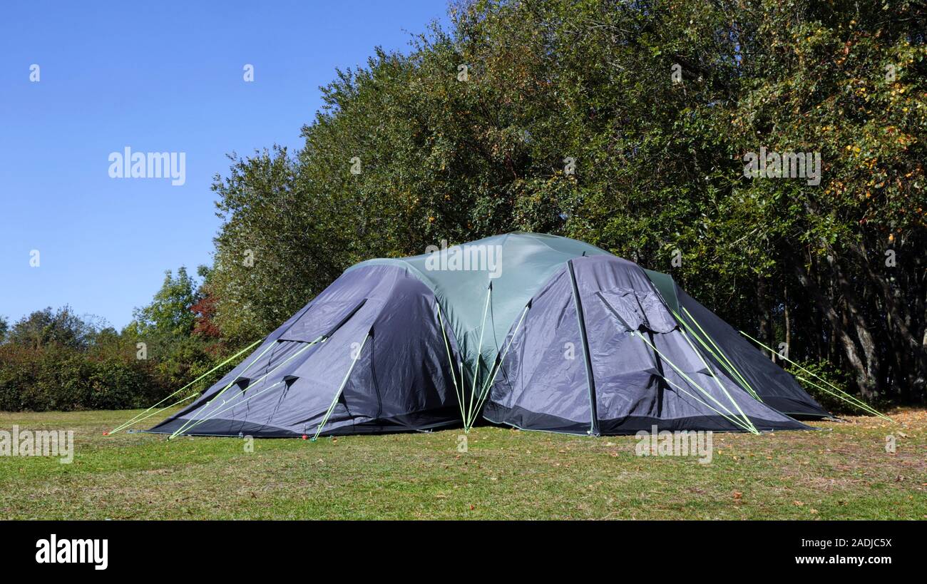 Big family camping tent on the edge of the meadow in the forest campsite, on a summer sunny day Stock Photo