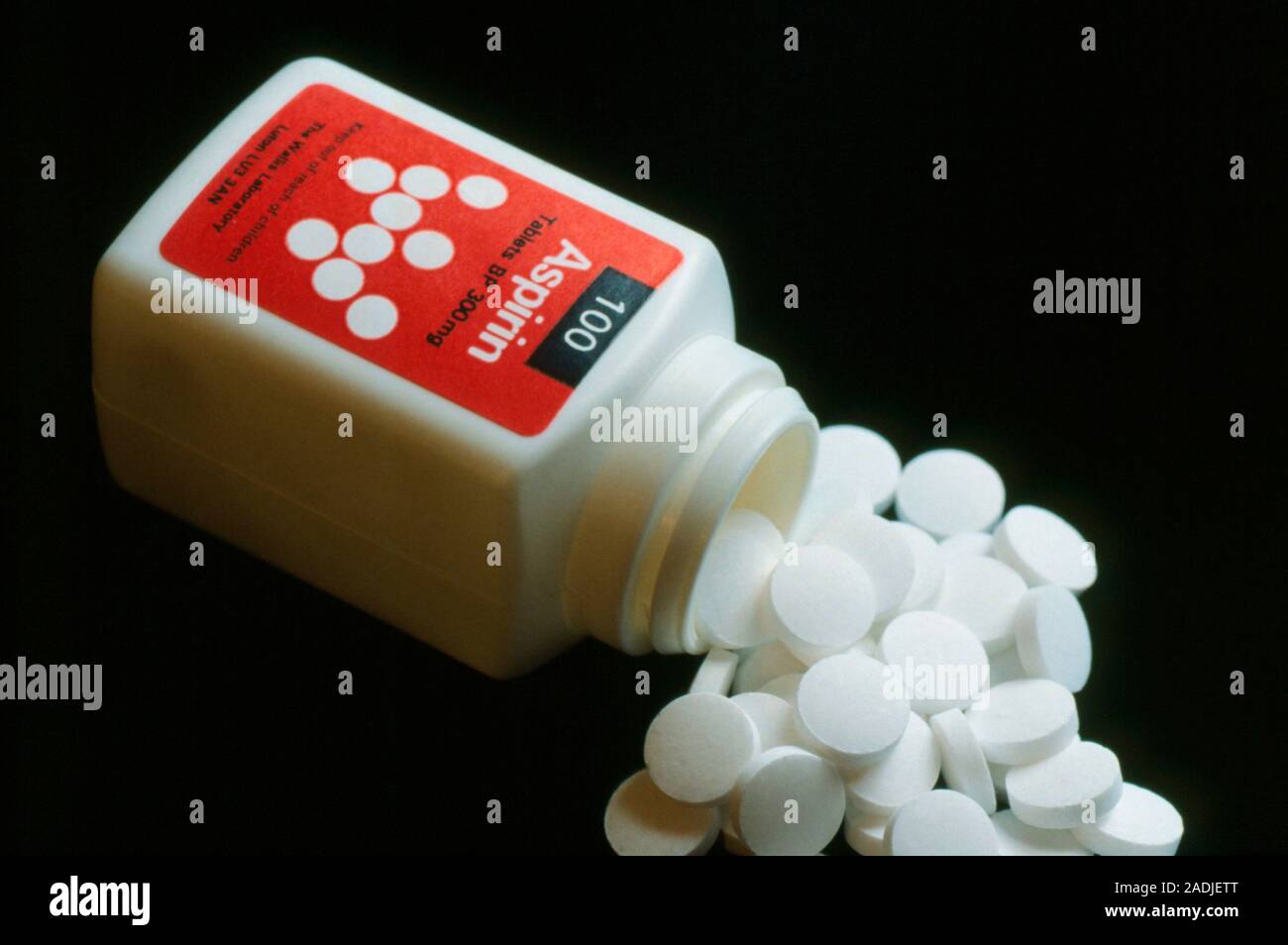 Bottle of aspirin (100), common analgesic, on side with mound of pills