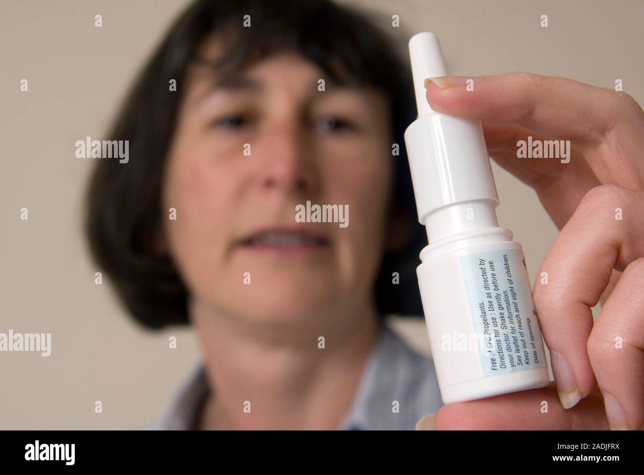 MODEL RELEASED. Woman using a nasal spray. Nasal sprays use a pump