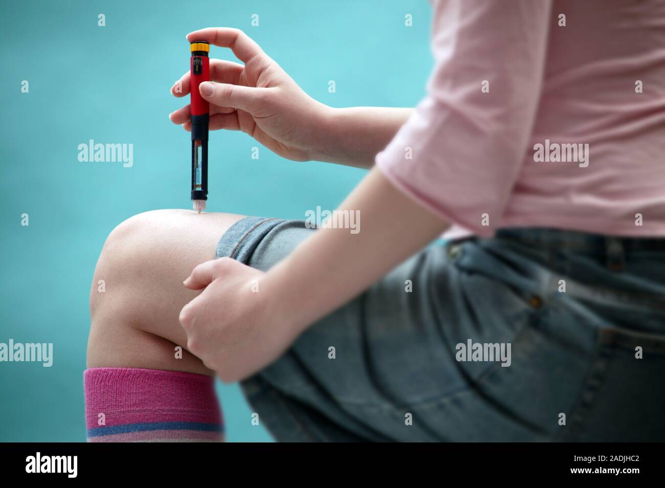 Insulin injection. Diabetic woman injecting herself in the leg with