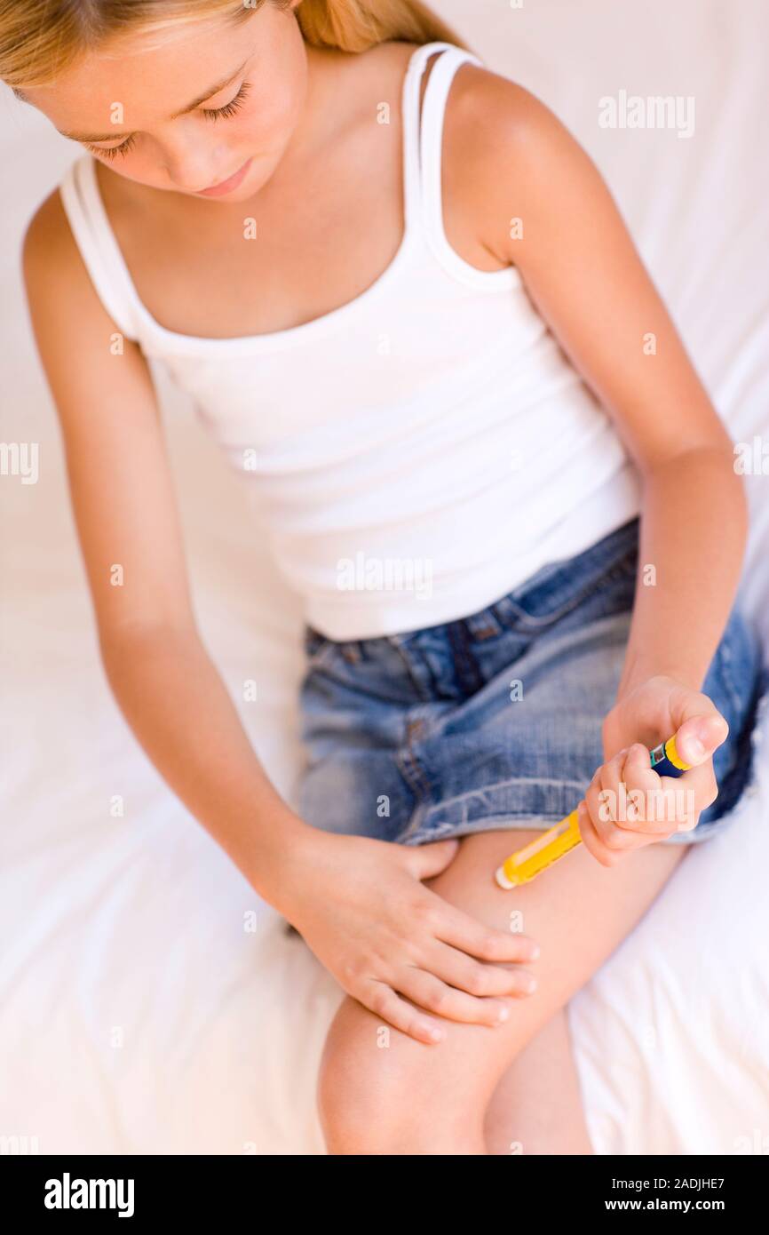 MODEL RELEASED. Insulin injection. Girl injecting insulin into her thigh to treat the disease