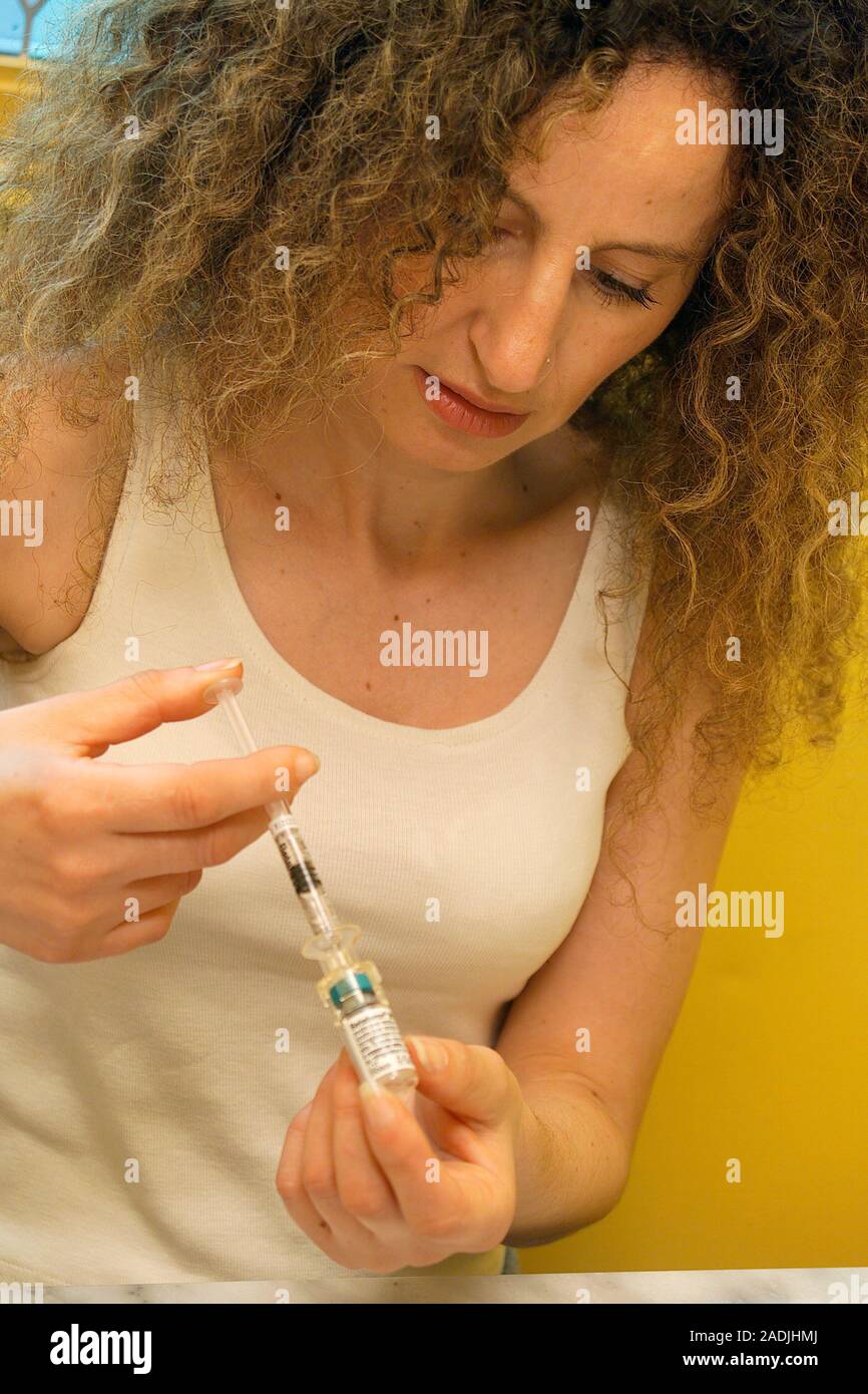 Multiple sclerosis treatment. Woman using a syringe to draw beta