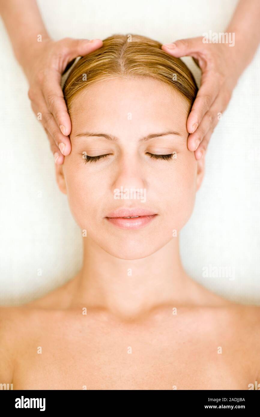 MODEL RELEASED. Massage. Woman receiving a temple massage. Massage can relieve muscular pain or