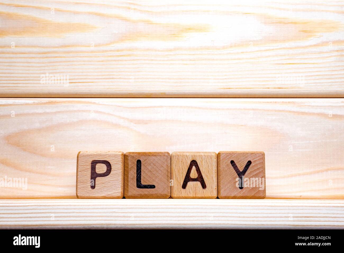 Word play written on wooden cubes on wooden background. Wooden cubes formed the word play. Online, dramatic play. For wood latin letters made the word play Stock Photo