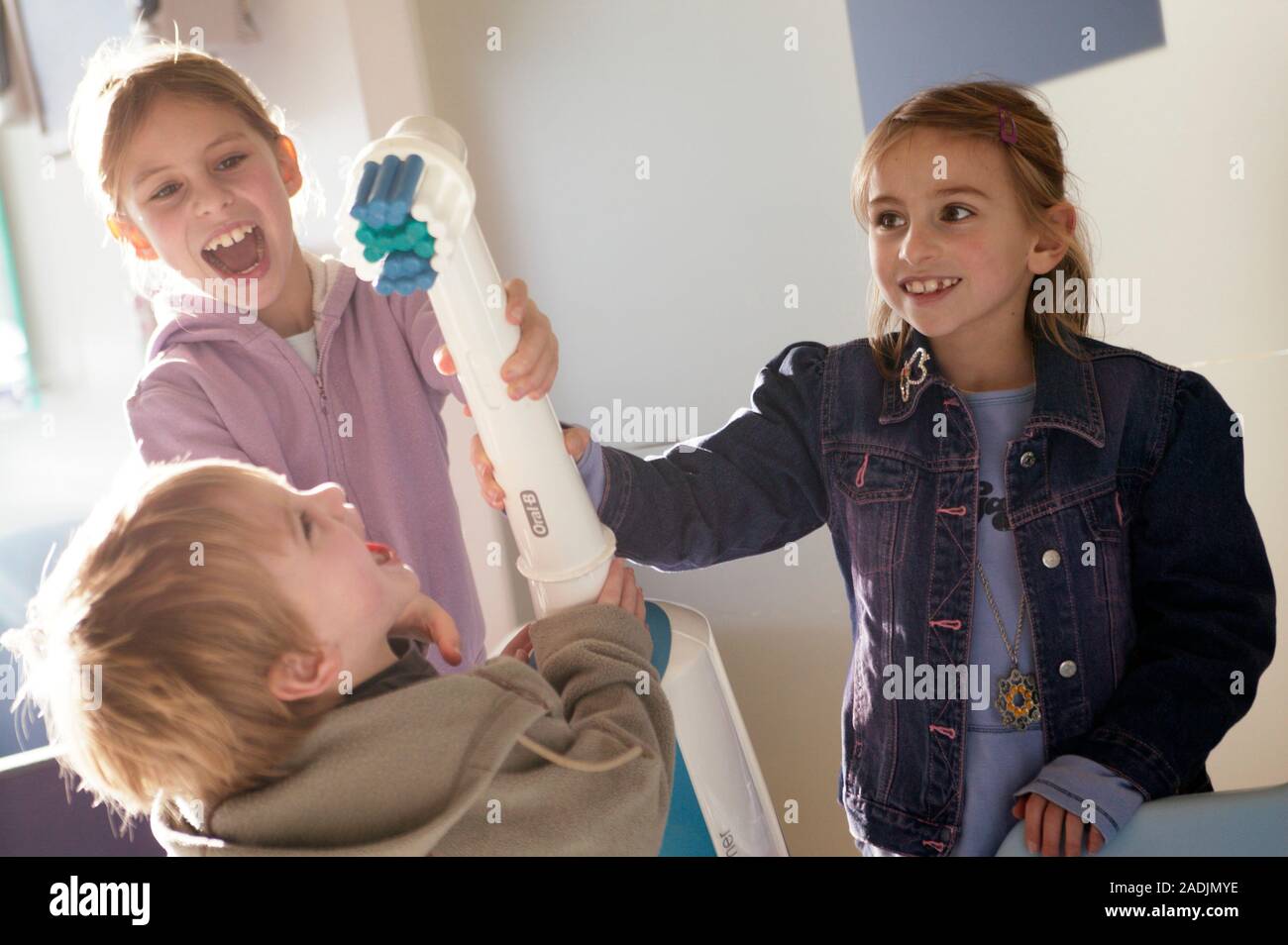 Toothbrush Playing Giant electric toothbrush. Three children playing with a giant electric ...