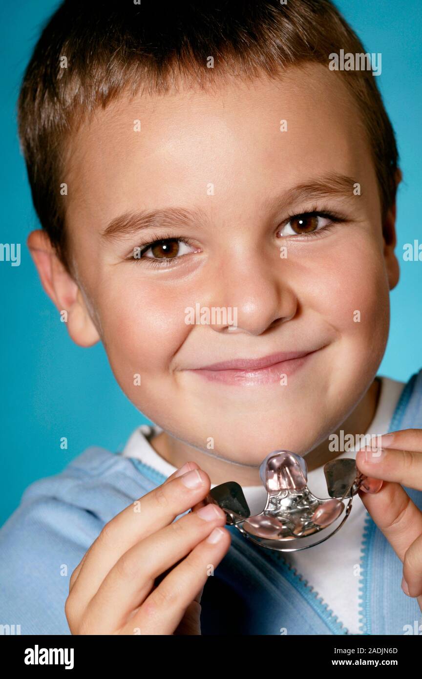 MODEL RELEASED. Young boy holding a dental retainer. A dental retainer