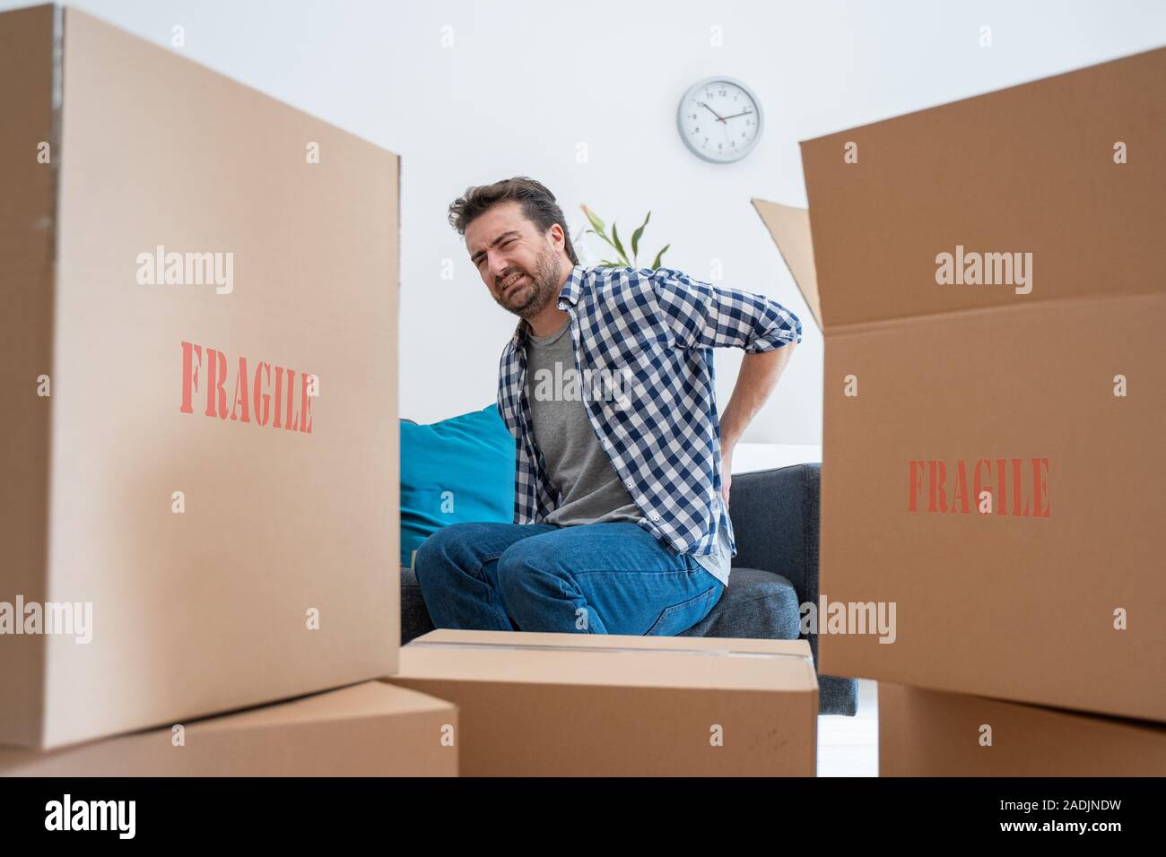 Man moving boxes and feeling back pain because heavy weight Stock Photo