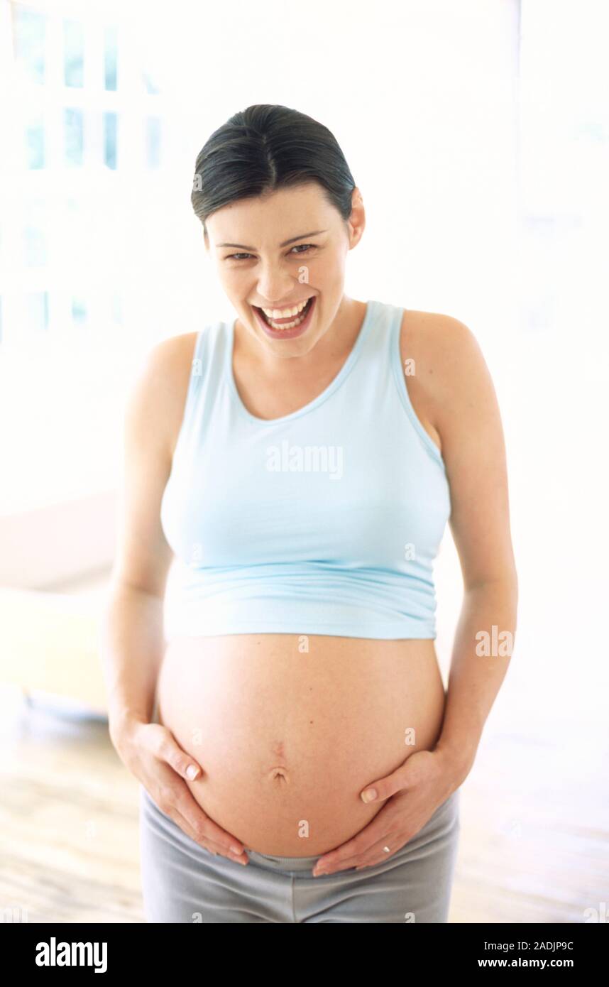 Pregnant Woman Smiling And Holding Her Hands Against Her Swollen Abdomen She Is Eight Months