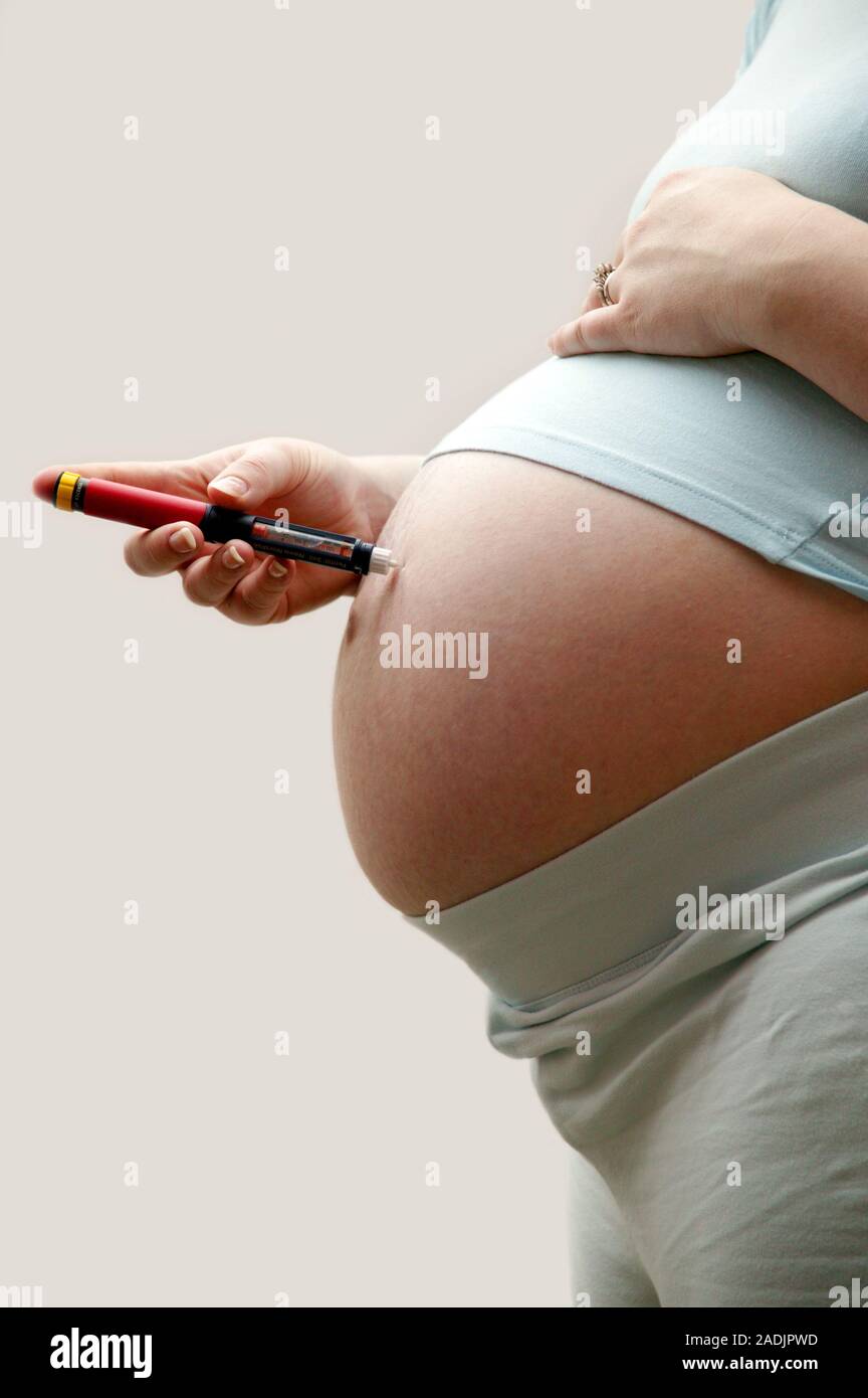 Insulin injection. Pregnant woman with diabetes injecting herself in the abdomen with insulin