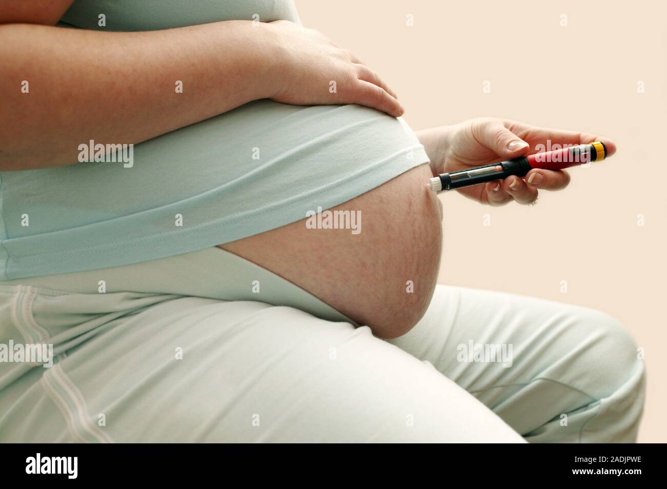 Insulin injection. Pregnant woman with diabetes injecting herself in