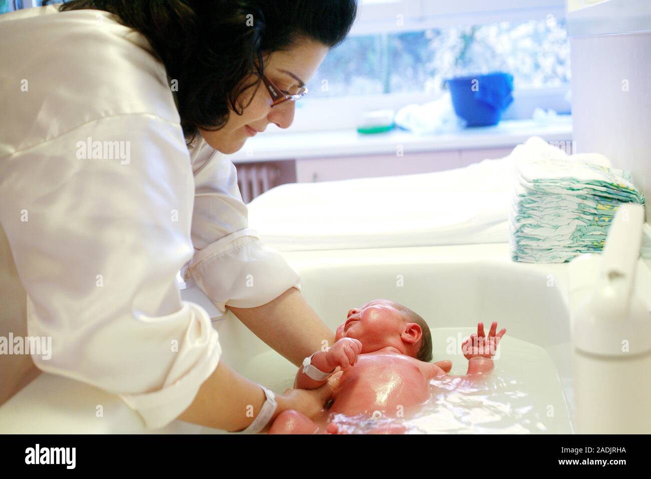 Newborn baby being bathed in a hospital. Mother washing her baby for
