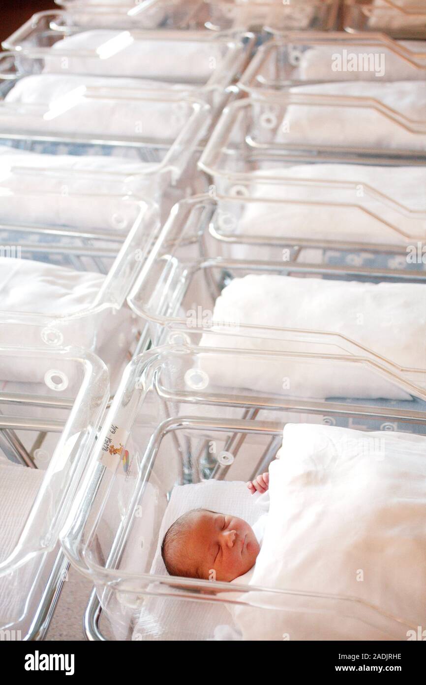 Newborn baby sleeping in a cot in a hospital's neonatal nursery Stock