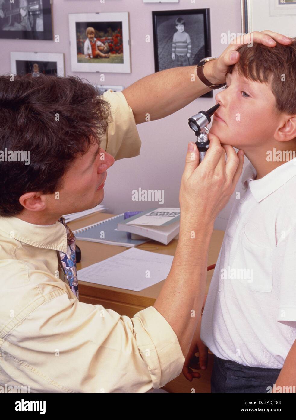 Nasal examination. A doctor examines a boy's nose using an otoscope. The otoscope consists of a
