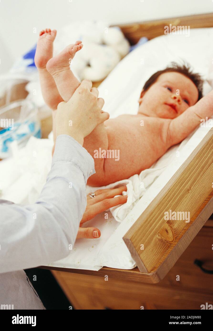 Baby girl having her nappy changed by her mother. She is two months old