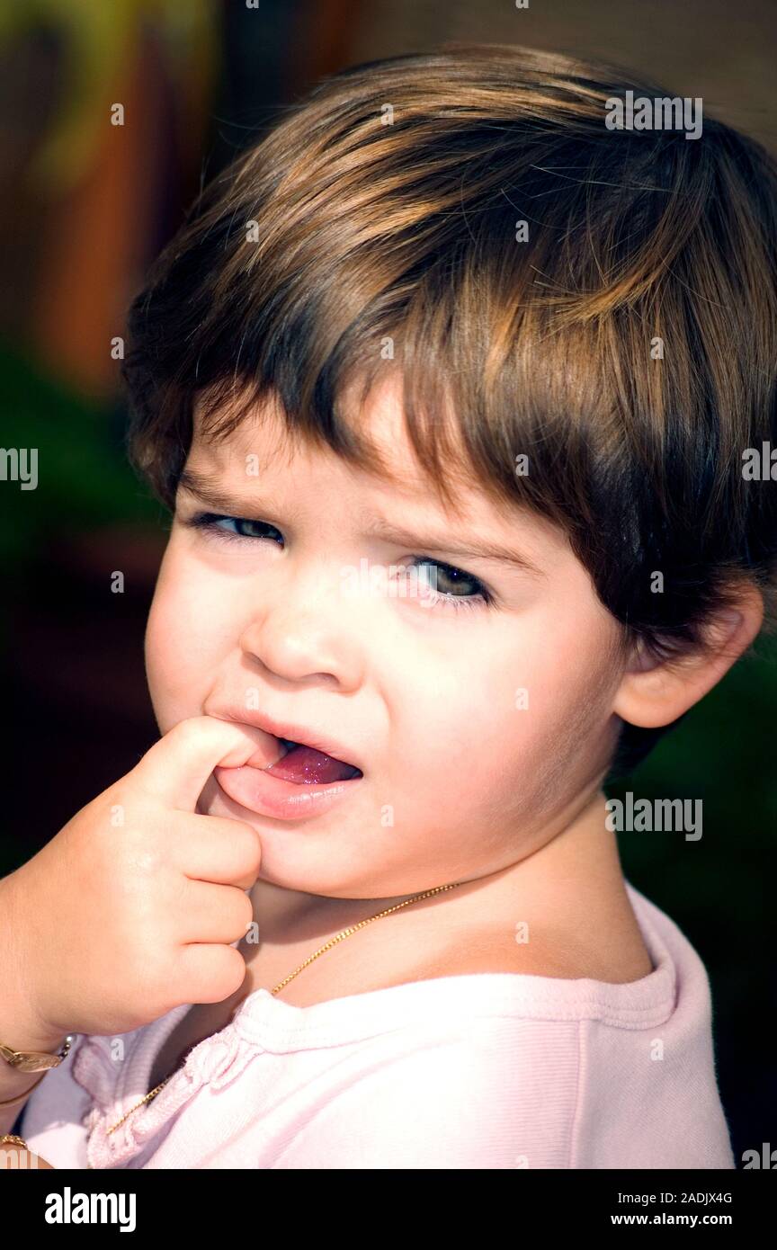 MODEL RELEASED. Teething. Three year old boy biting his finger Stock