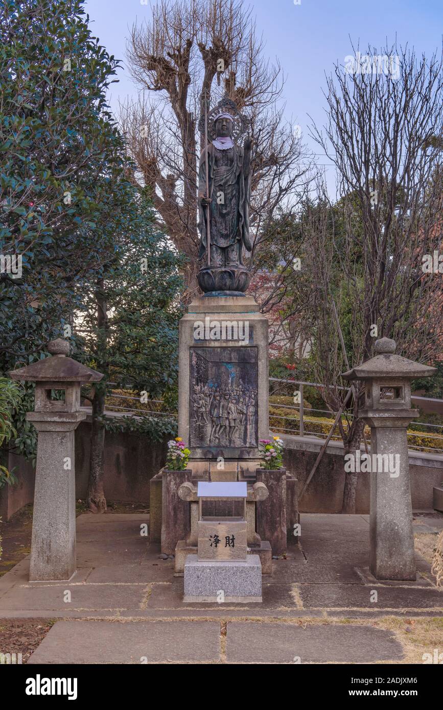 Statue of Jizo on a pedestal where Japanese ideographs of the protector