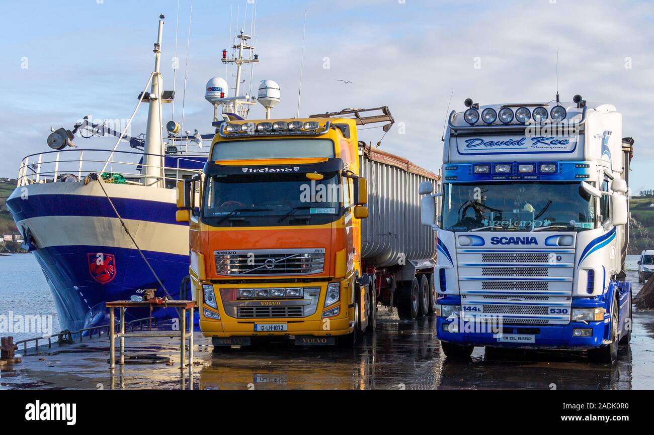 Volvo and Scania Trucks parked on a jetty next to a trawler Stock Photo