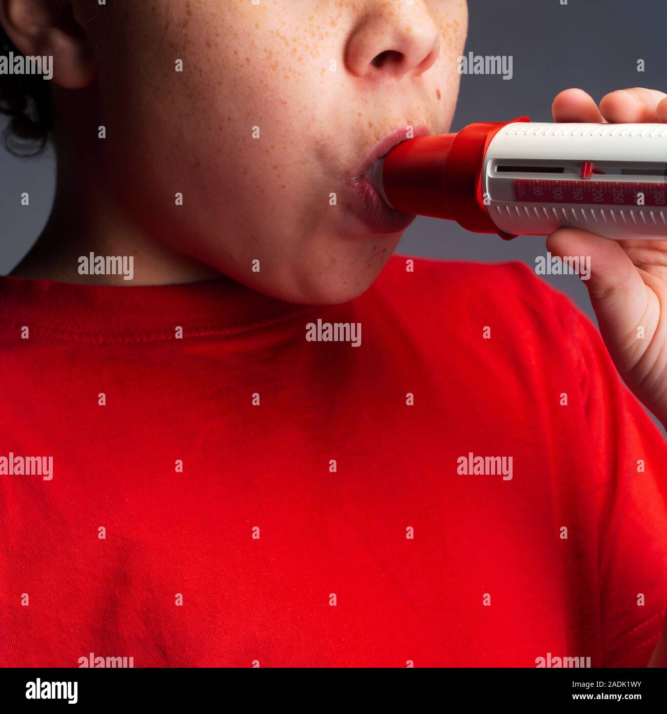 Lung function test. Boy breathing into a peak flow meter (spirometer
