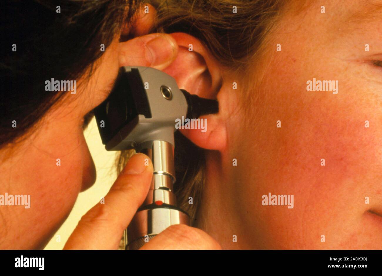 A nurse conducts a routine ear examination on a woman, using an