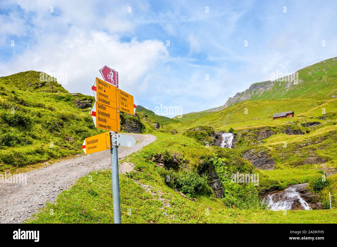 Yellow tourist sign on the path from Grindelwald leading to Bachalpsee lake in Switzerland. Information sign giving distances and directions to hikers in the Swiss Alps. Summer Alpine landscape. Stock Photo