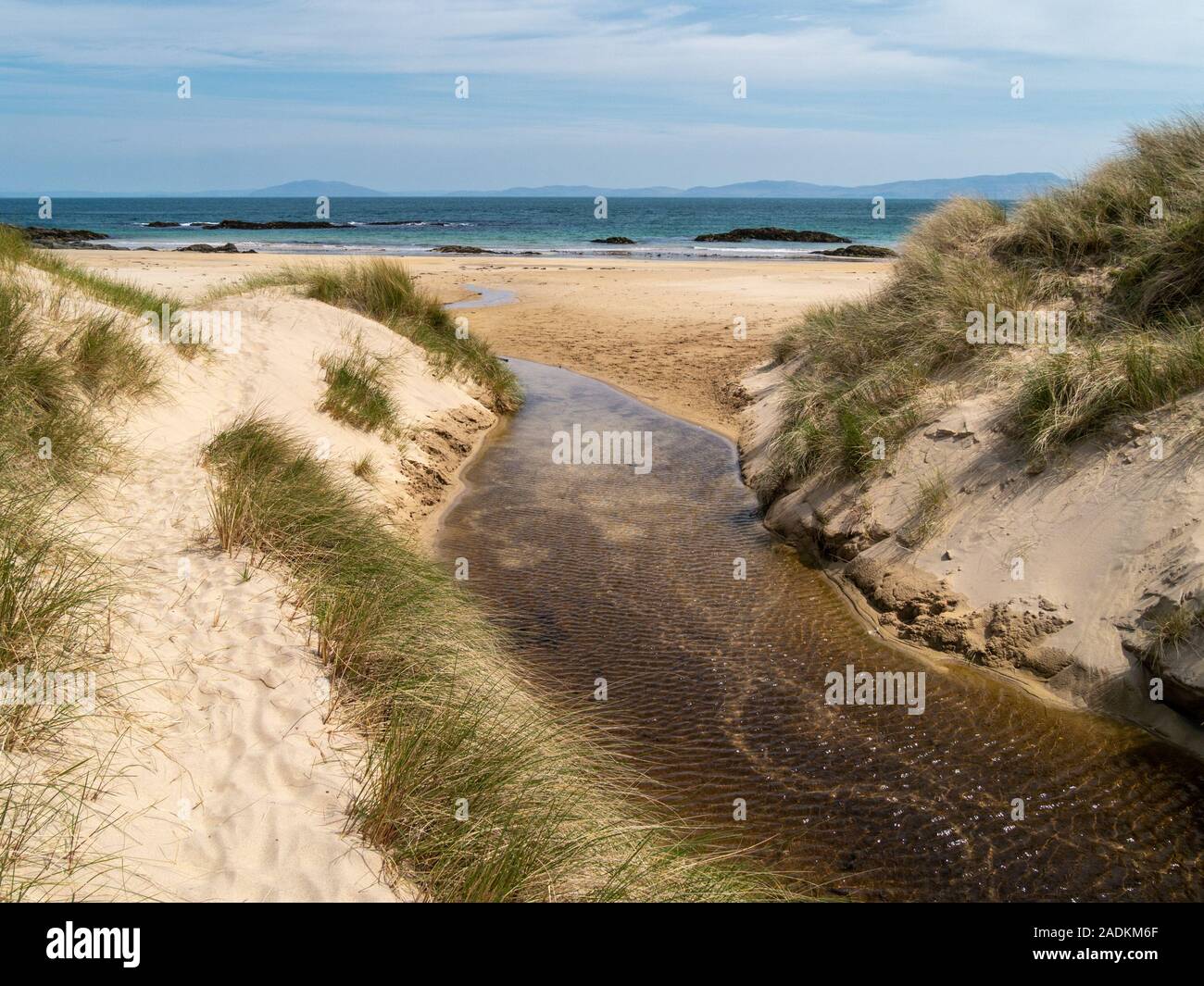 Stream running between sand dunes with Marram Grass onto Balnahard beach, Isle of Colonsay in the Inner Hebrides, Scotland Stock Photo