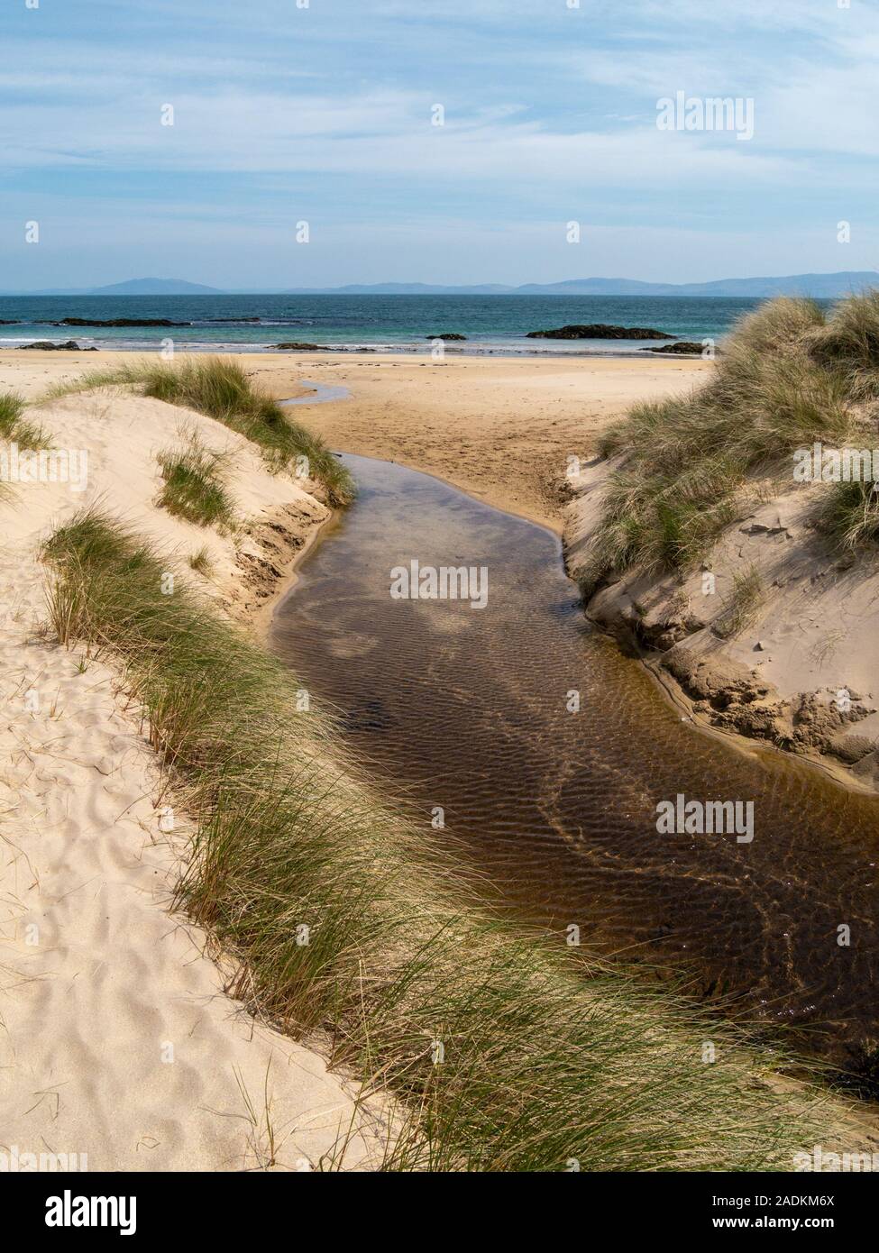 Stream running between sand dunes with Marram Grass onto Balnahard beach, Isle of Colonsay in the Inner Hebrides, Scotland Stock Photo