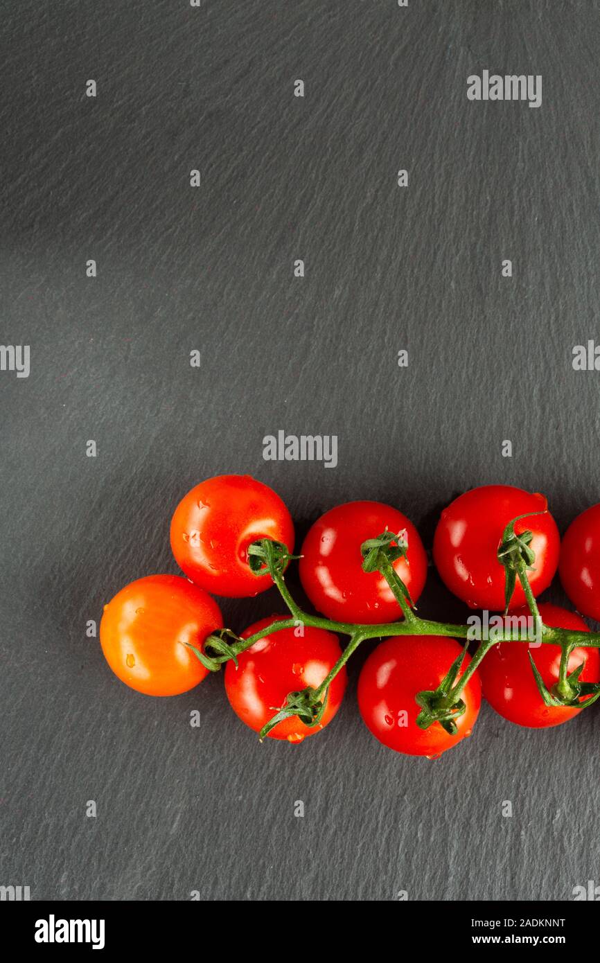 Cherry tomatoes branch at the bottom of vertical photo Stock Photo - Alamy
