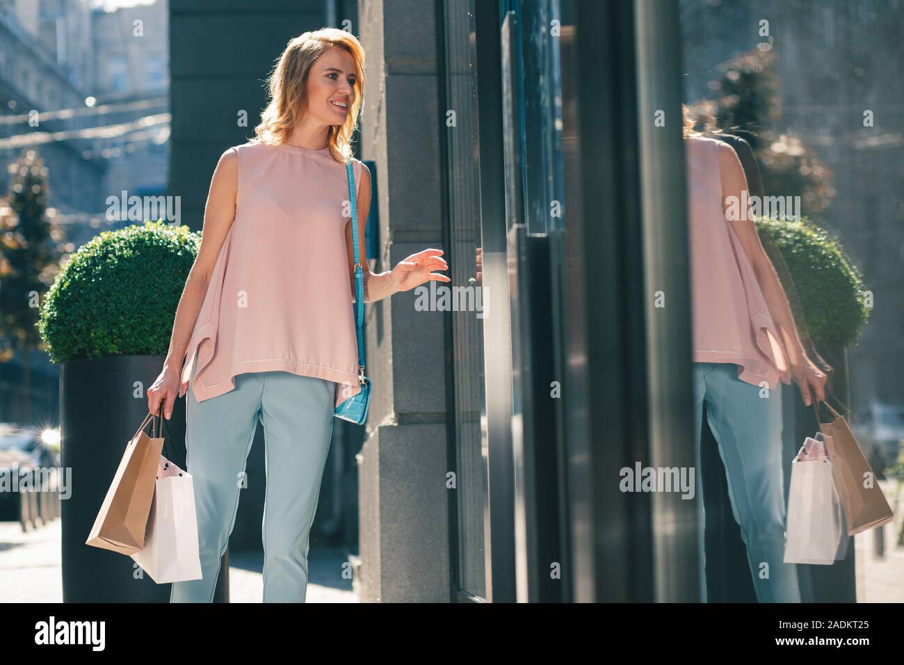 Young adult woman smiling near the glass window Stock Photo