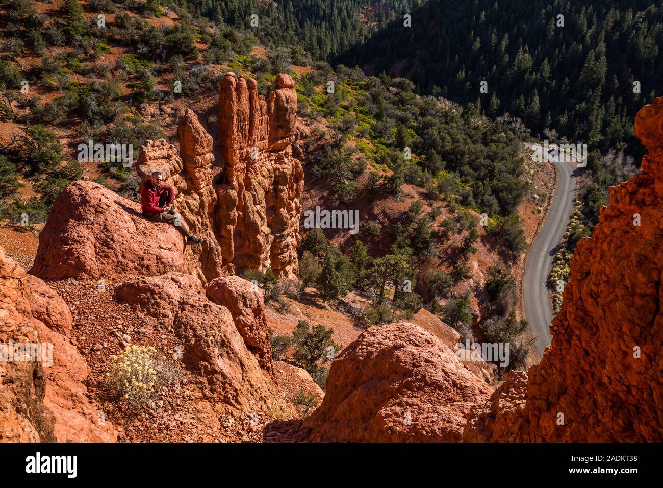 Man looking toward the camera resting atop red rock formations in Southern Utah canyon near Cedar City. Stock Photo