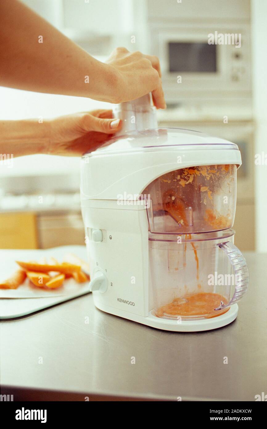 Juicing carrots. The electrical juicer is pulping raw carrots to make a